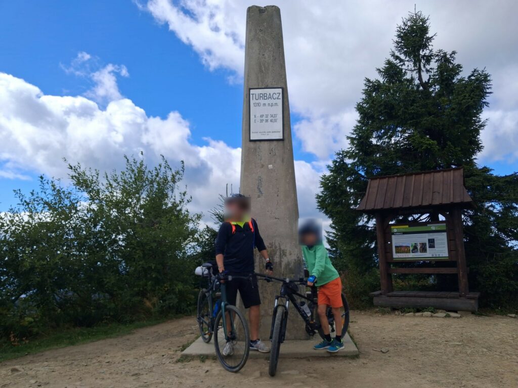 Ojciec i syn z rowerami przy obelisku na szczycie Turbacza (1310 m n.p.m.)